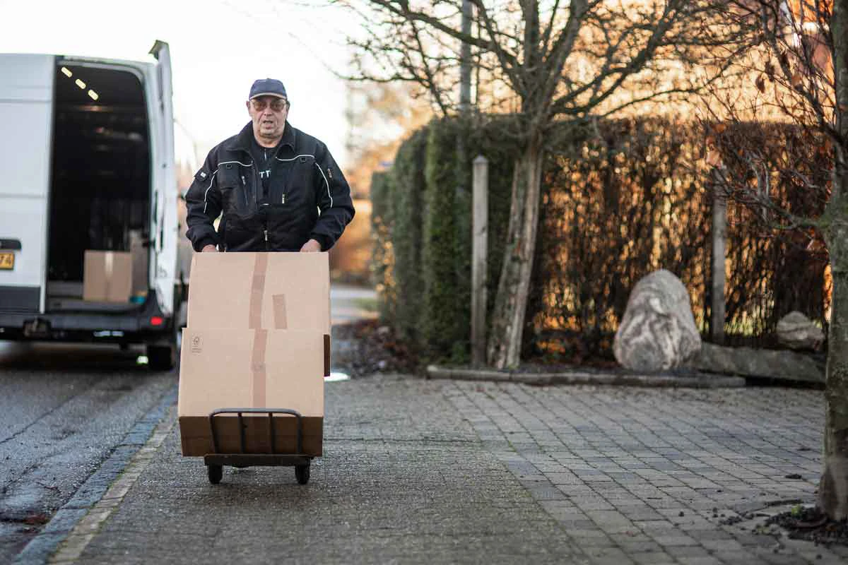 Transport bud transporterer to store kasser på en sækkevogn.