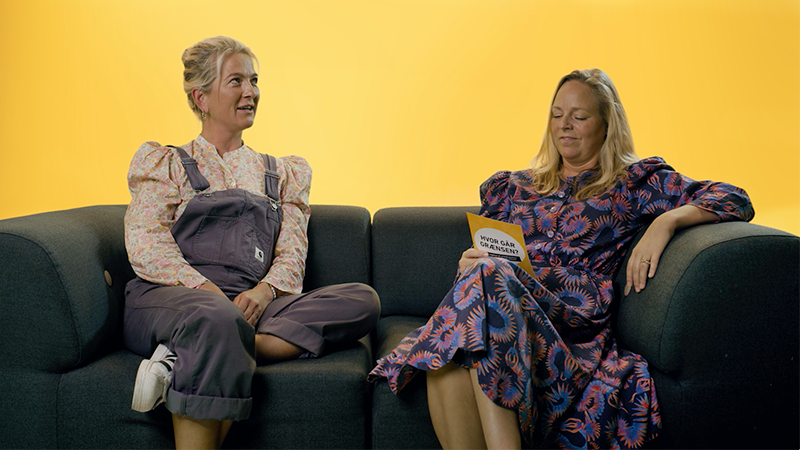 To kvinder sidder i sofa og benytter dialogkort