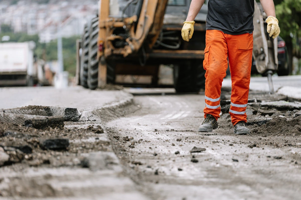 Asfaltarbejder arbejder på en vej hvor asfalten er blevet fjernet.