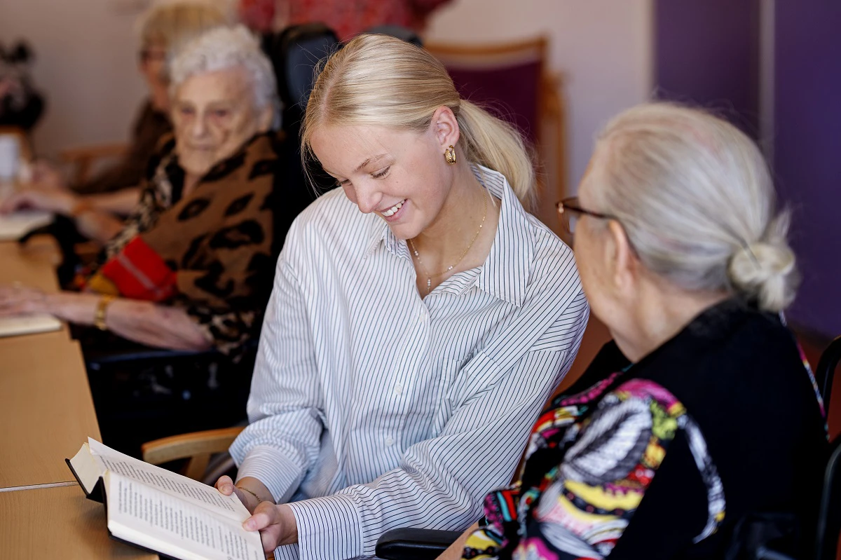 Pige læser op for ældre kvinde.
