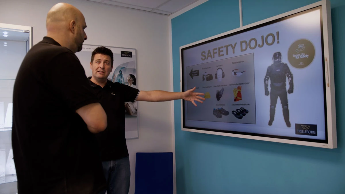  To mænd står foran en skærm, som viser forskellige sikkerhedsforanstaltninger. 