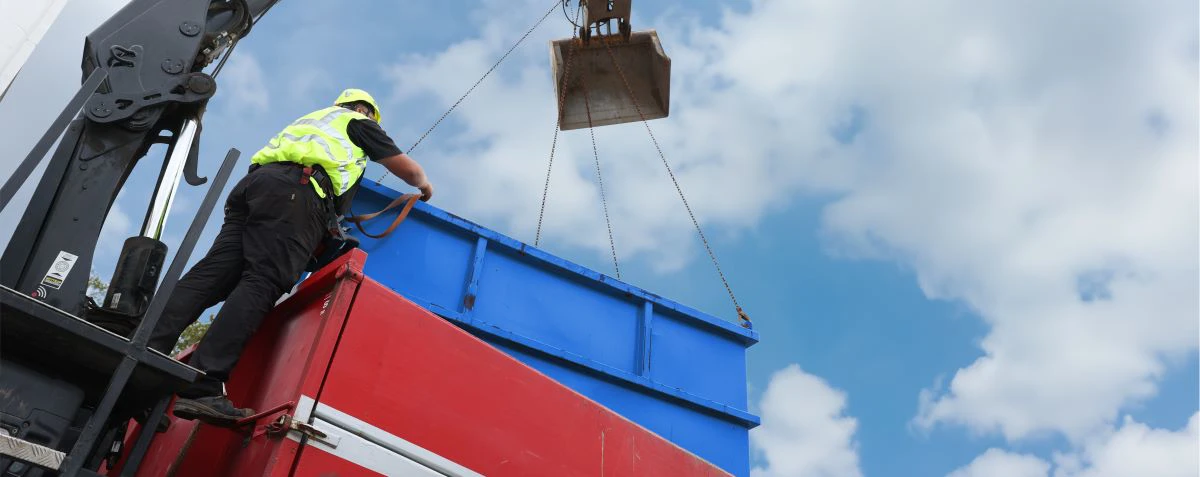 En container bliver løftet op fra en lastbil.