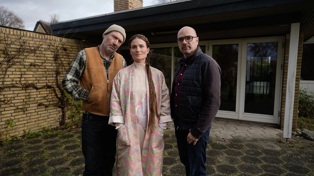 To mænd og en kvinde står udenfor og kigger ind i kameraet