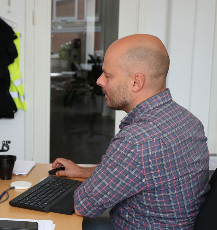 Mand sidder ved computer. 