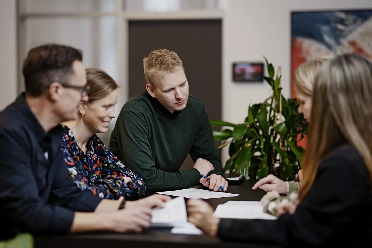 5 personer sidder og snakker hen over et bord