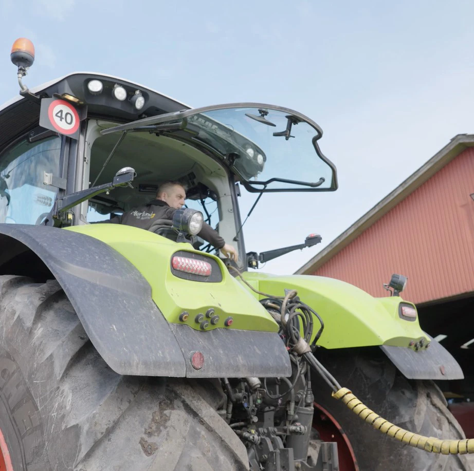Mand sidder i traktor med bagvindue åbent og kigger bagud.